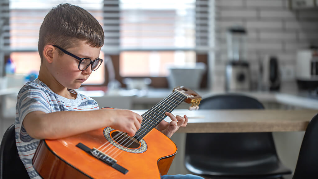 تصویر کودک در حال تمرین کردن با ساز گیتار